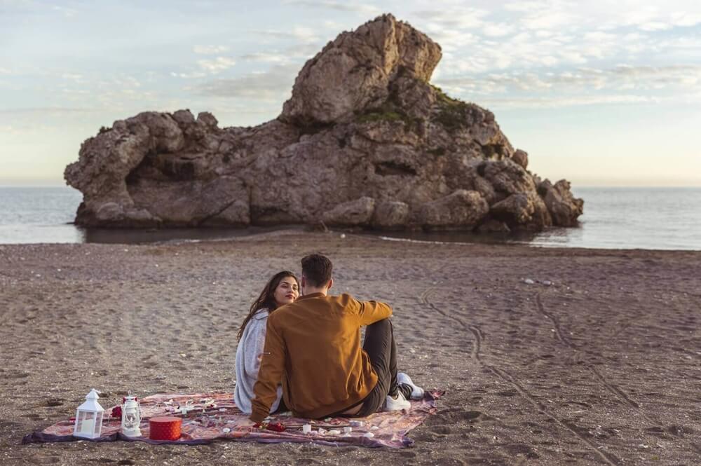 young couple sitting coverlet sea shore