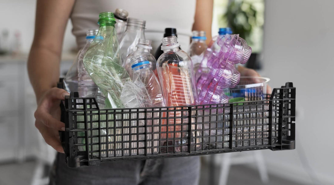 A woman holding a crate filled with plastic bottles for recycling, she is wearing a white shirt and jeans