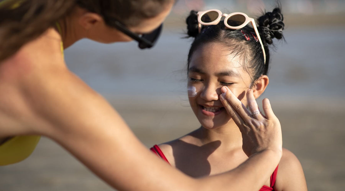 front-view of a woman applying sunscreen to her cute kid for sun protection